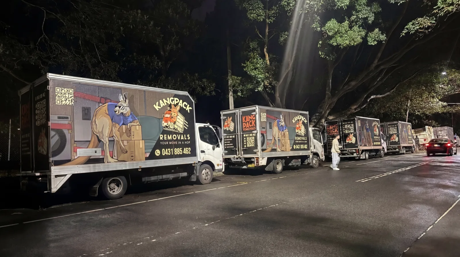 A line of KangPack removalist trucks parked on a tree-lined Eastern Suburbs street