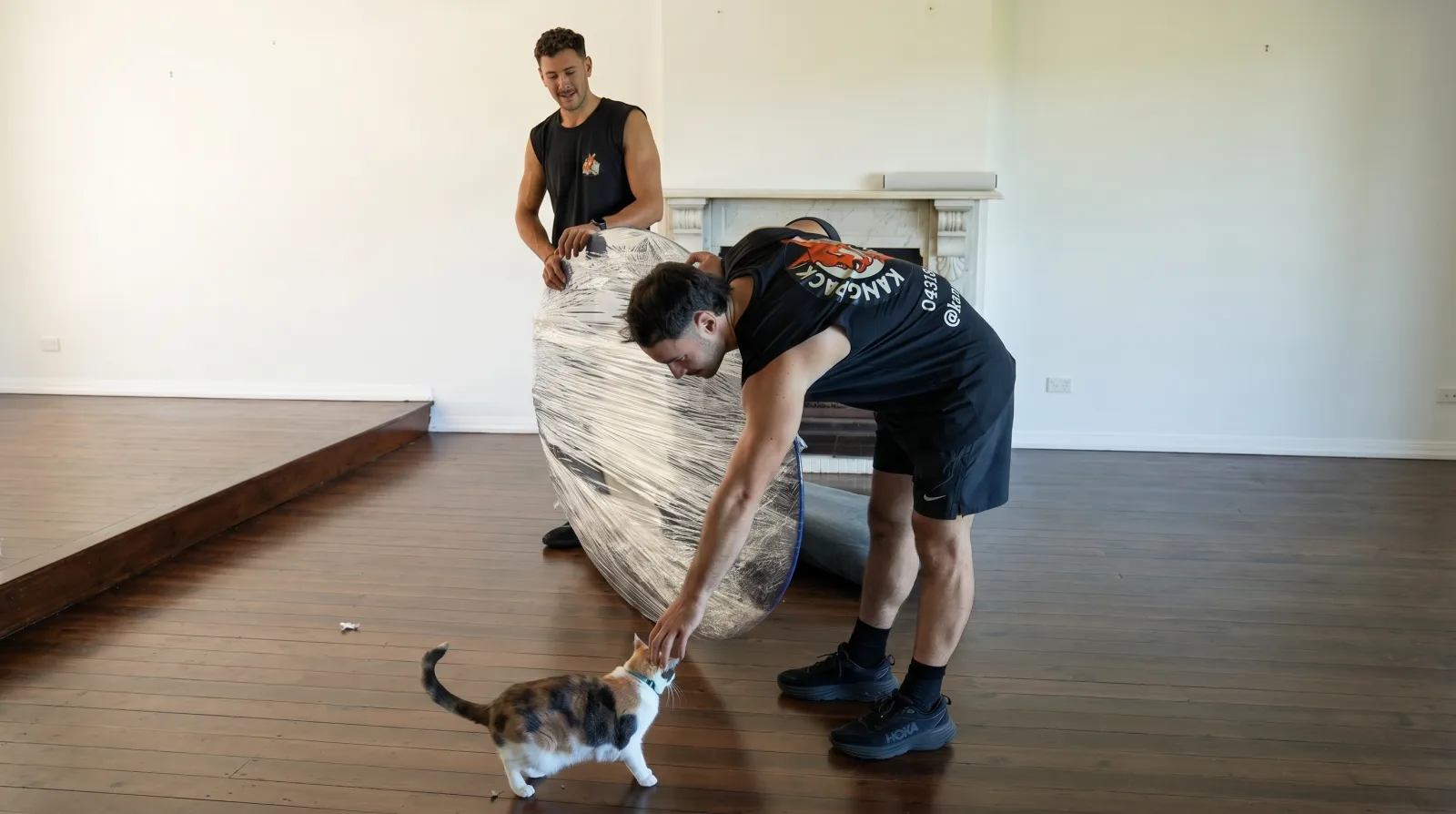 KangPack removalists wrapping a table while a cat watches during a Maroubra move